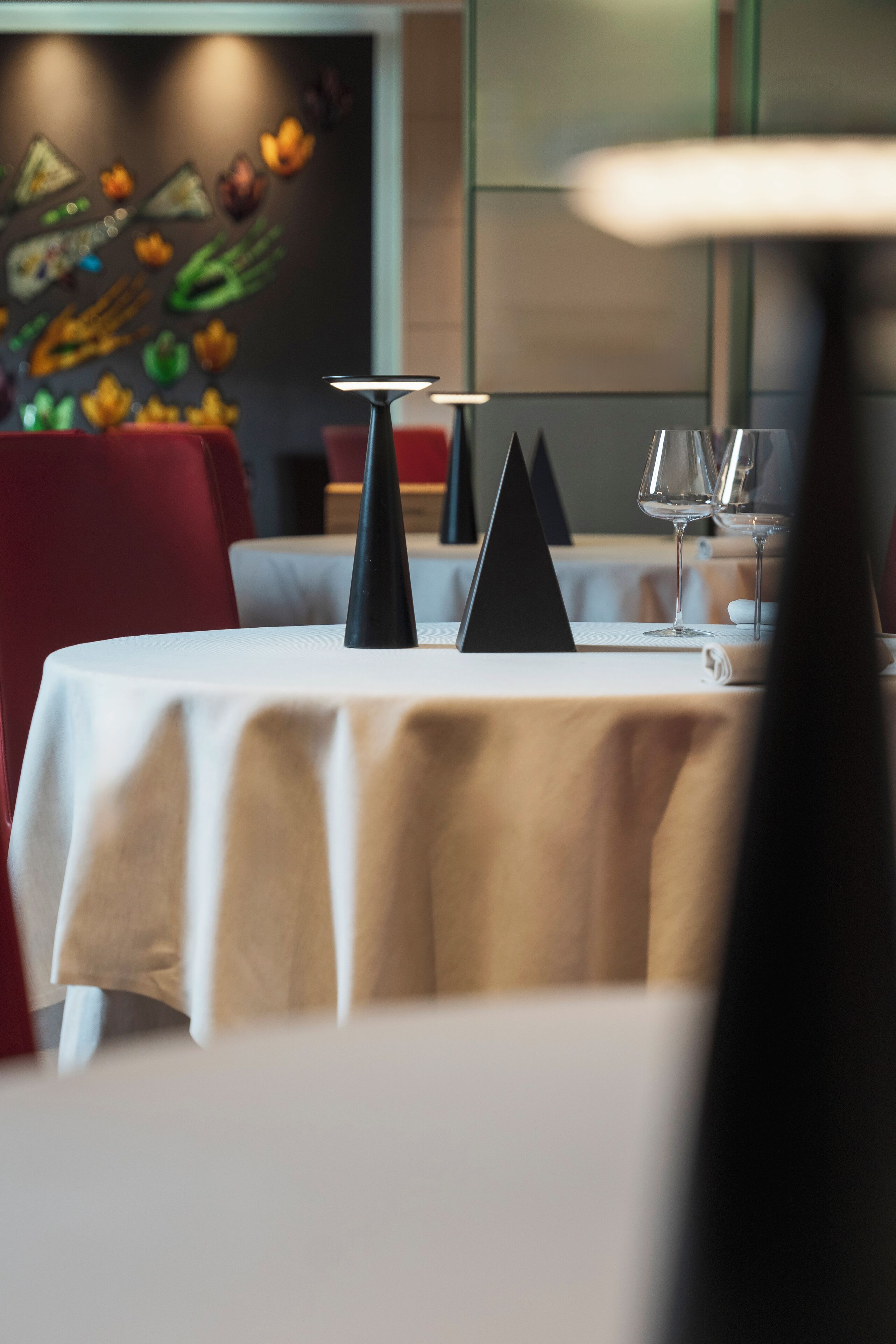 A dining table set with a white tablecloth, black centerpieces, and wine glasses.