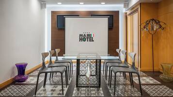 Una sala riunioni con uno schermo proiettore che mostra il logo del MAREI HOTEL, un tavolo da conferenza e sei sedie.