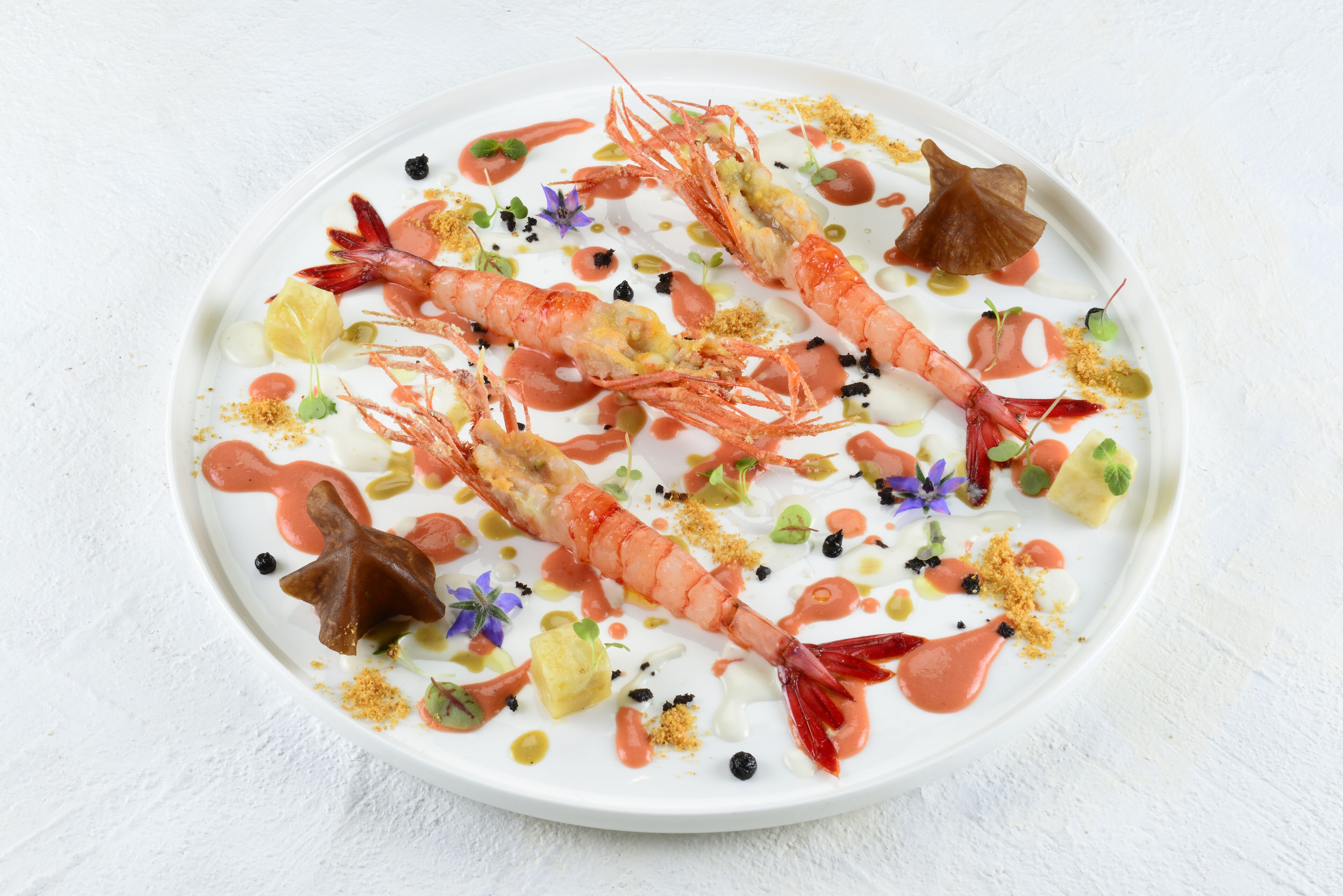 A plate with two prawns, garnishes, and sauces.