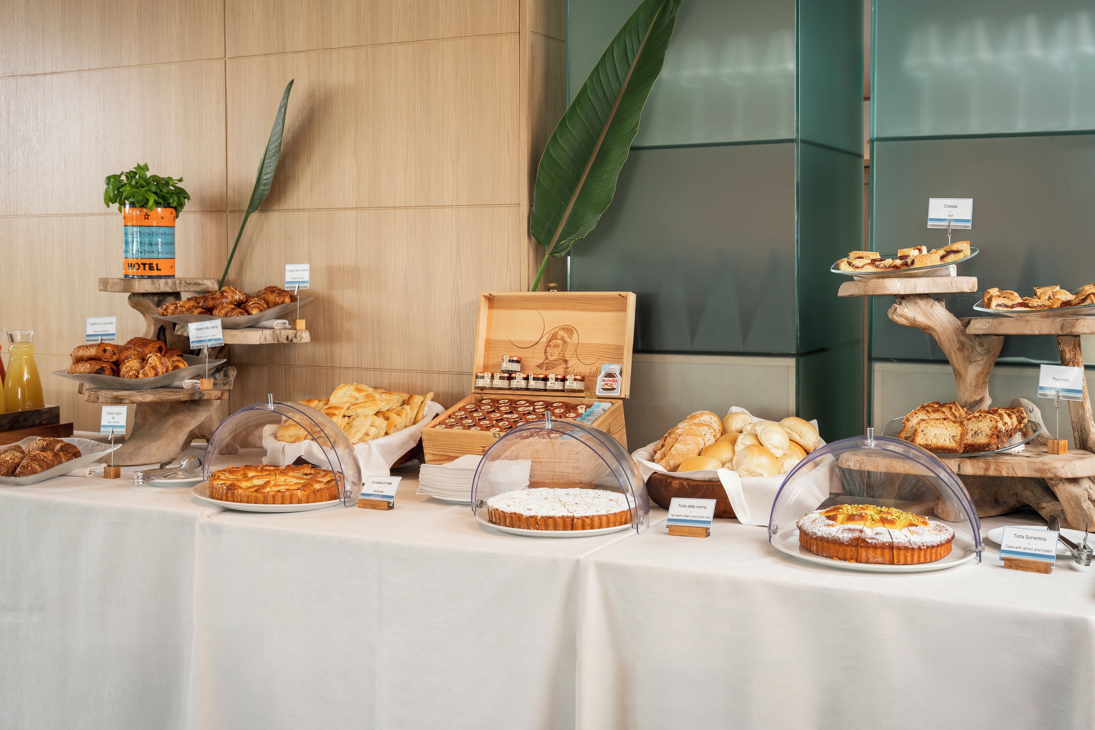 A buffet with various pastries and desserts, including cakes and bread, displayed on a table with a white tablecloth.