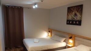 A hotel room with two beds, a wooden headboard, a painting on the wall, and a curtain. - Logis Hôtel Acotel (Le Pontet)