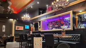 A restaurant with booths, tables, and a motorcycle-themed wall. - Logis Hôtel Acotel (Le Pontet)
