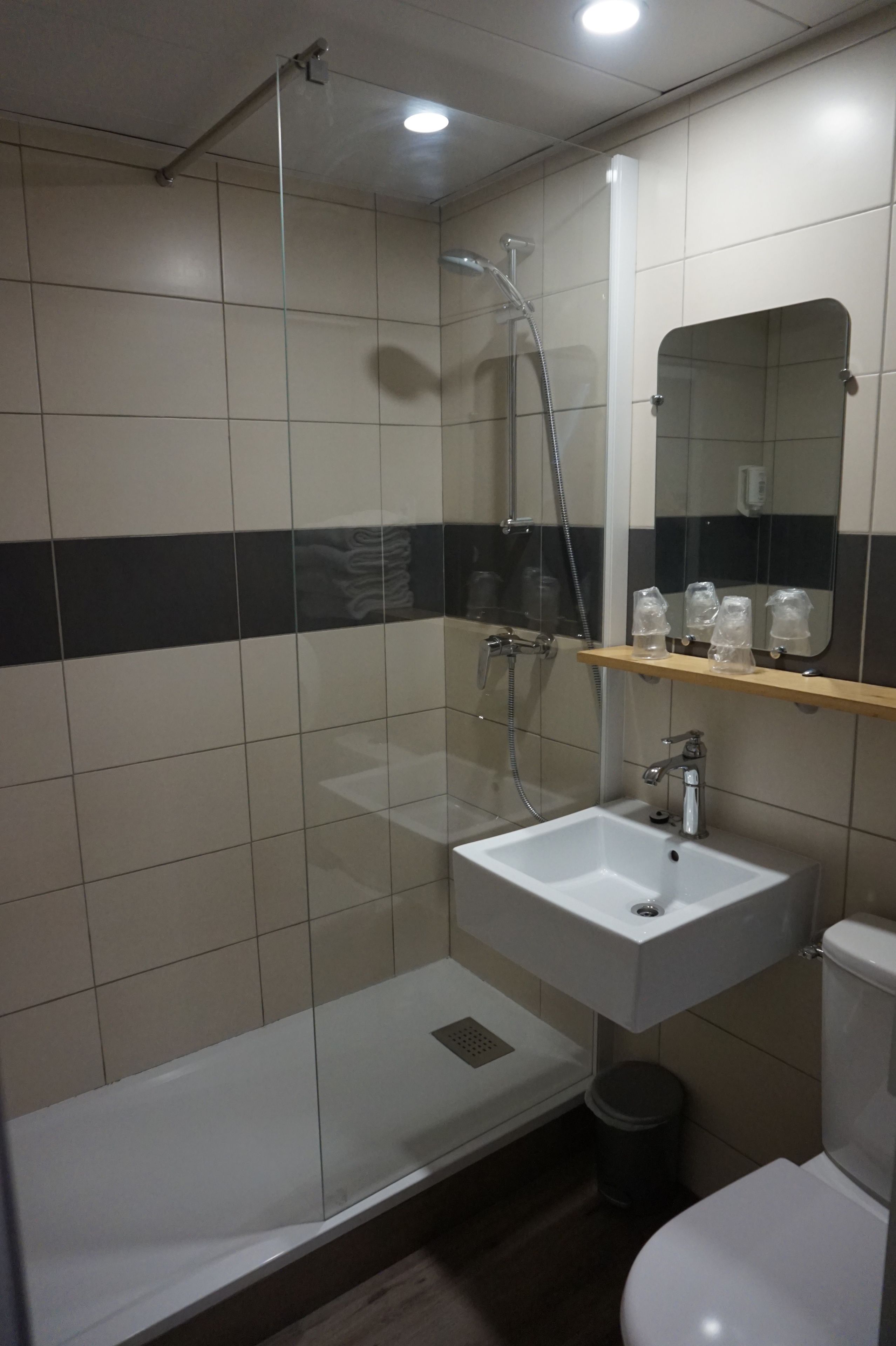 A modern bathroom with a glass-enclosed shower, a white sink, and a mirror above it.