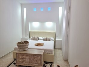 Un dormitorio moderno con cama, mesitas de noche y cabecera con iluminación integrada.