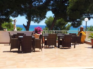 Un patio al aire libre con muebles de mimbre, un jarrón grande y una estatua.