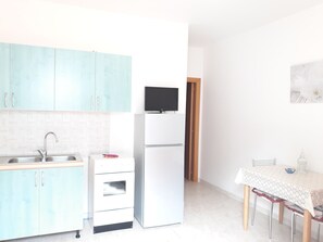 Una cocina compacta con armarios azul claro, un refrigerador blanco y un horno pequeño.
