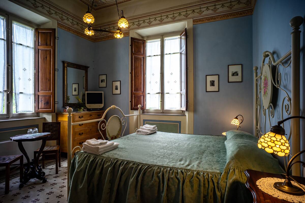 A bedroom with a bed, dresser, vanity, and a desk.