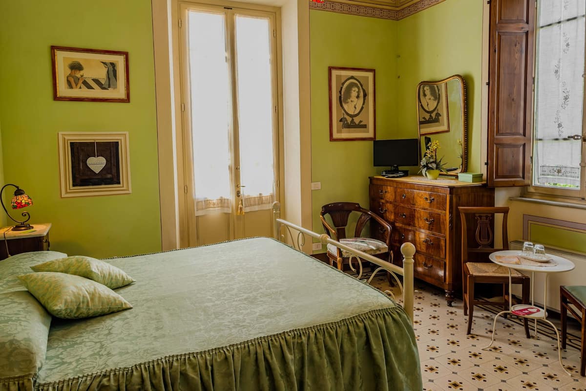 A room with a bed, a desk, a chair, a dresser, and a window.