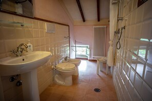 Un baño con lavamanos, dos inodoros, ducha y ventana con vistas.