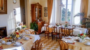 A dining area with multiple tables set for service, wooden chairs, and a large mirror above the counter. - Marta Guest House (Lucca)