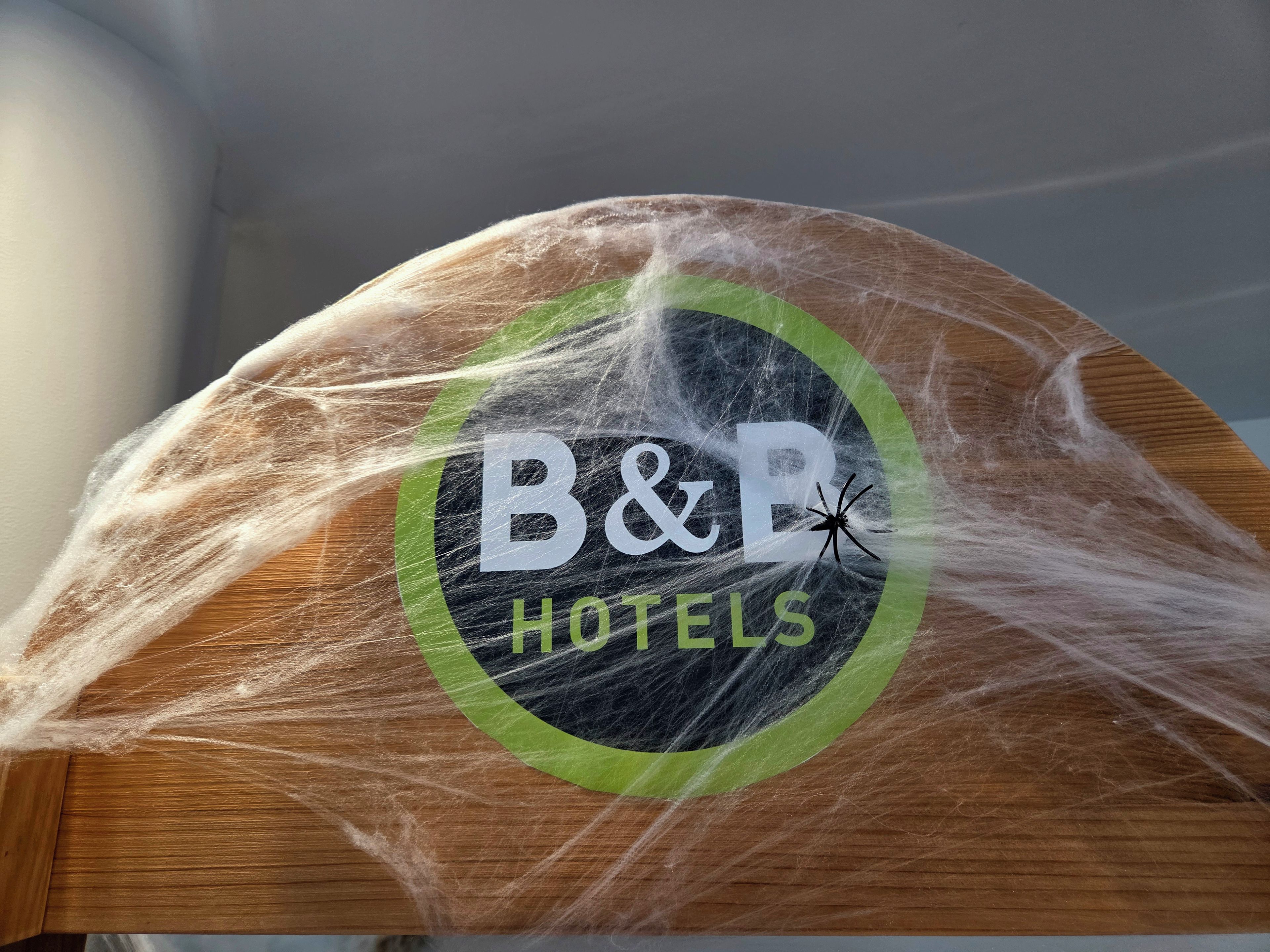 Un objet en bois orné d’un logo sur lequel on peut lire « B&B HOTELS » et d’un motif représentant une araignée.