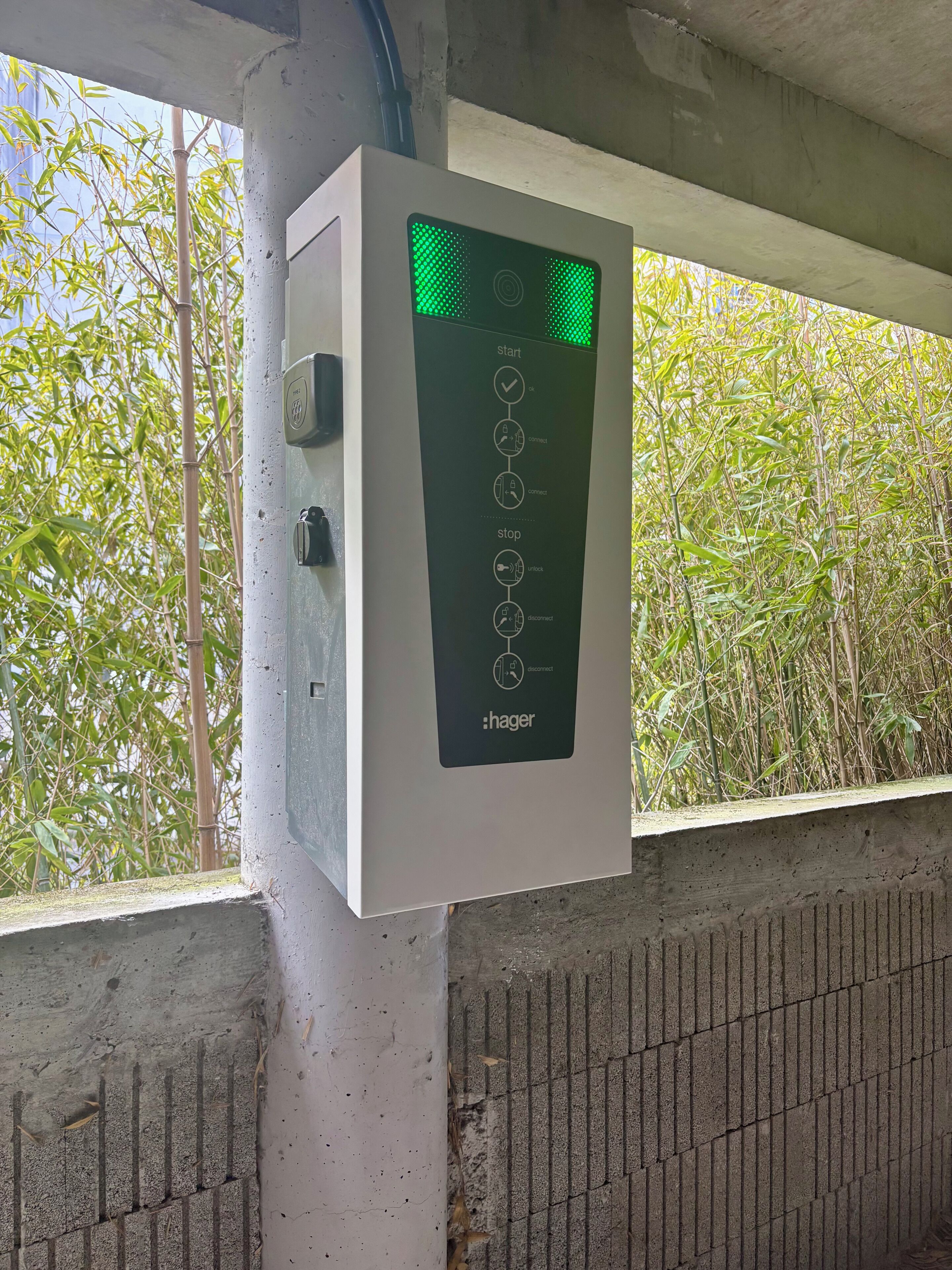 Een bedieningspaneel bevestigd aan een betonnen paal, met bamboe op de achtergrond.