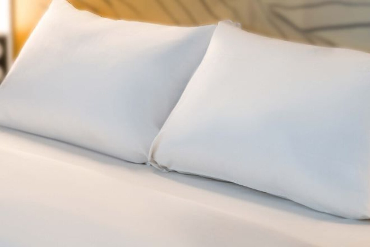 A white pillow on a bed.