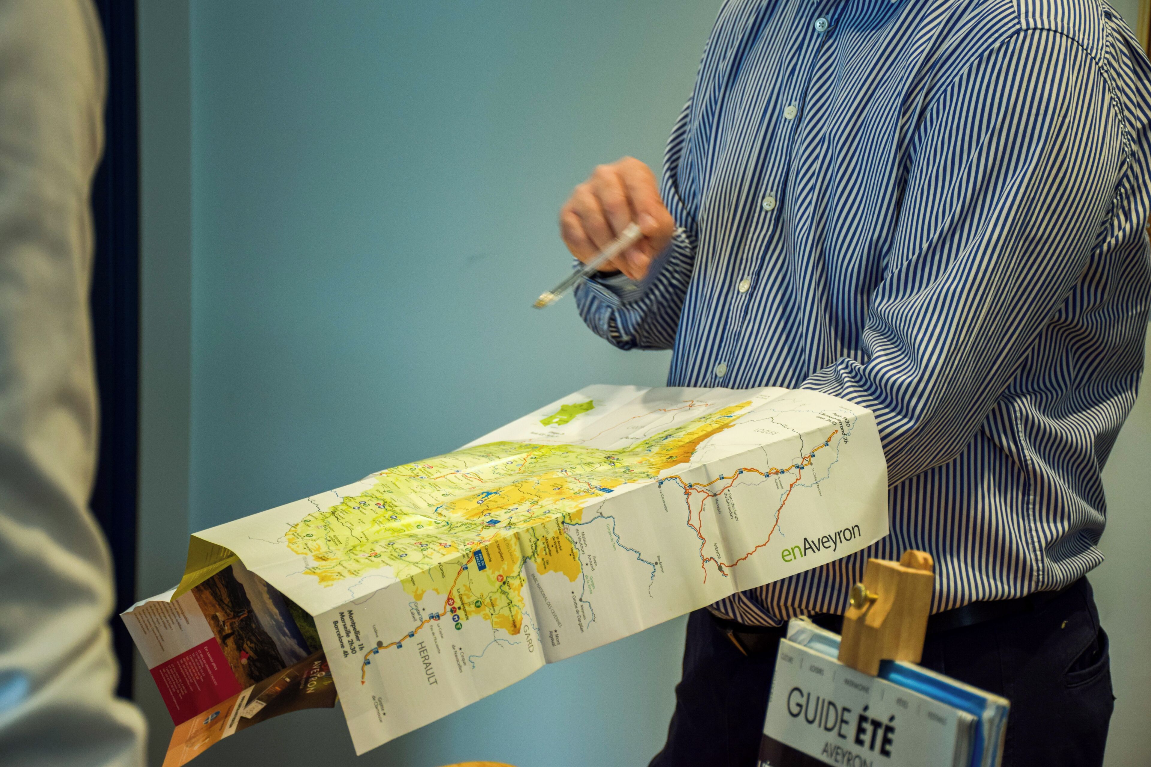 A person holding a large map with a label 'enAveyron'.
