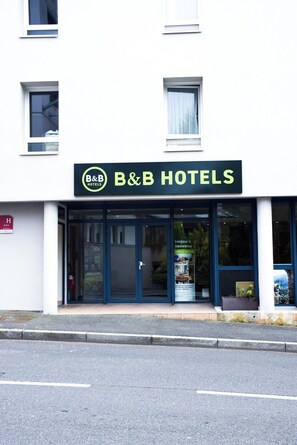 A B&B hotel with a prominent sign, large windows, and a fire hydrant on the sidewalk.