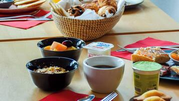 A breakfast table with various food items, including bowls of cereal, yogurt, and pastries.