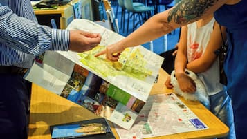 A person pointing at a map on a table, with a laptop and brochures nearby.