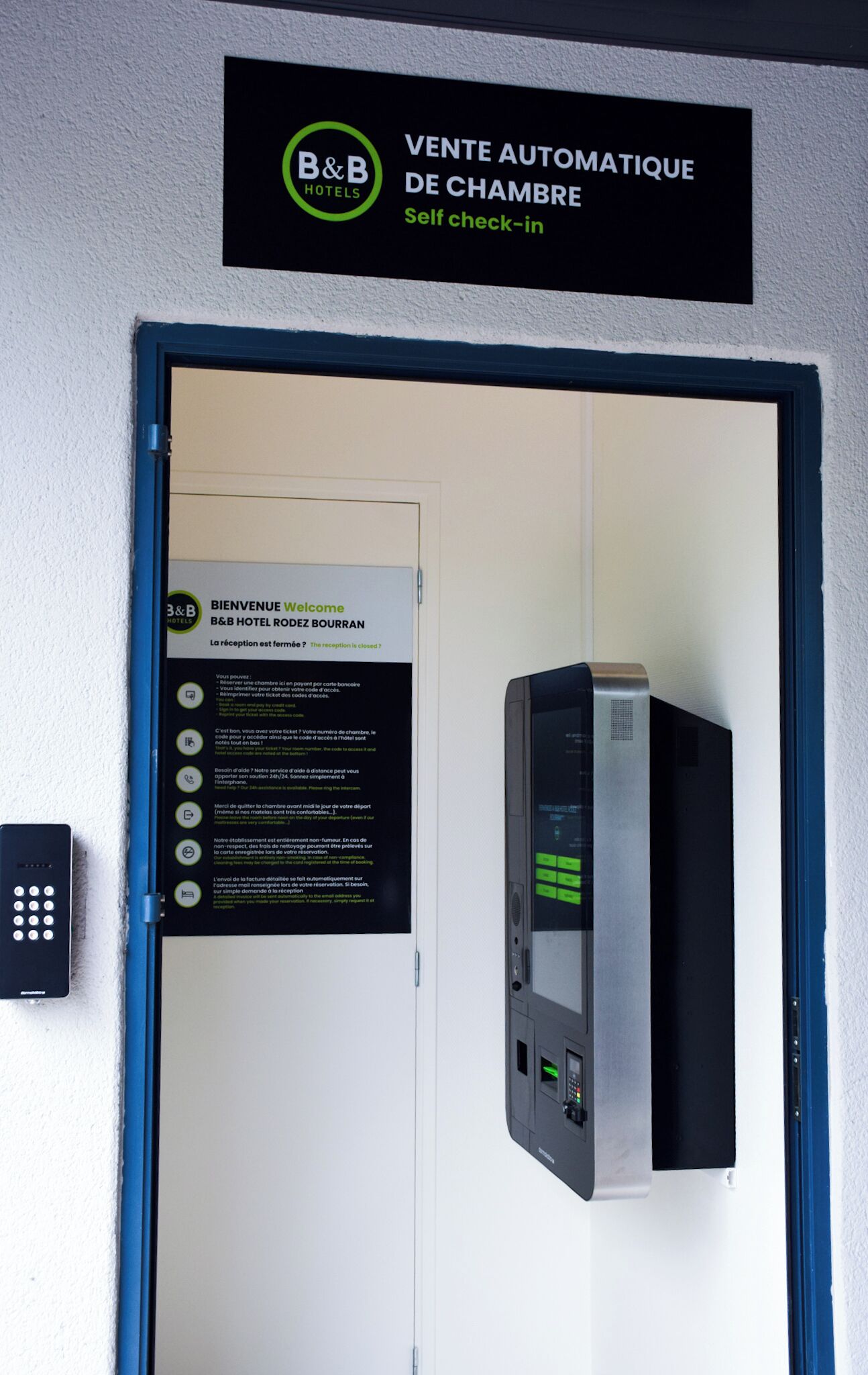 A self-service check-in kiosk at B&B Hotel Rozan, with instructions and a keypad.