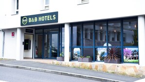 Ein Bed & Breakfast Hotel mit moderner Fassade, großen Fenstern und Pflanzen in Töpfen vor der Tür.