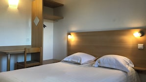 Quarto de hotel com cama, duas mesas de cabeceira, escrivaninha e uma cadeira.