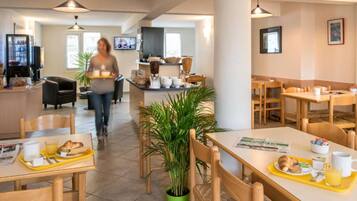 Een restaurantgedeelte in een hotel met tafels, stoelen en een buffet.