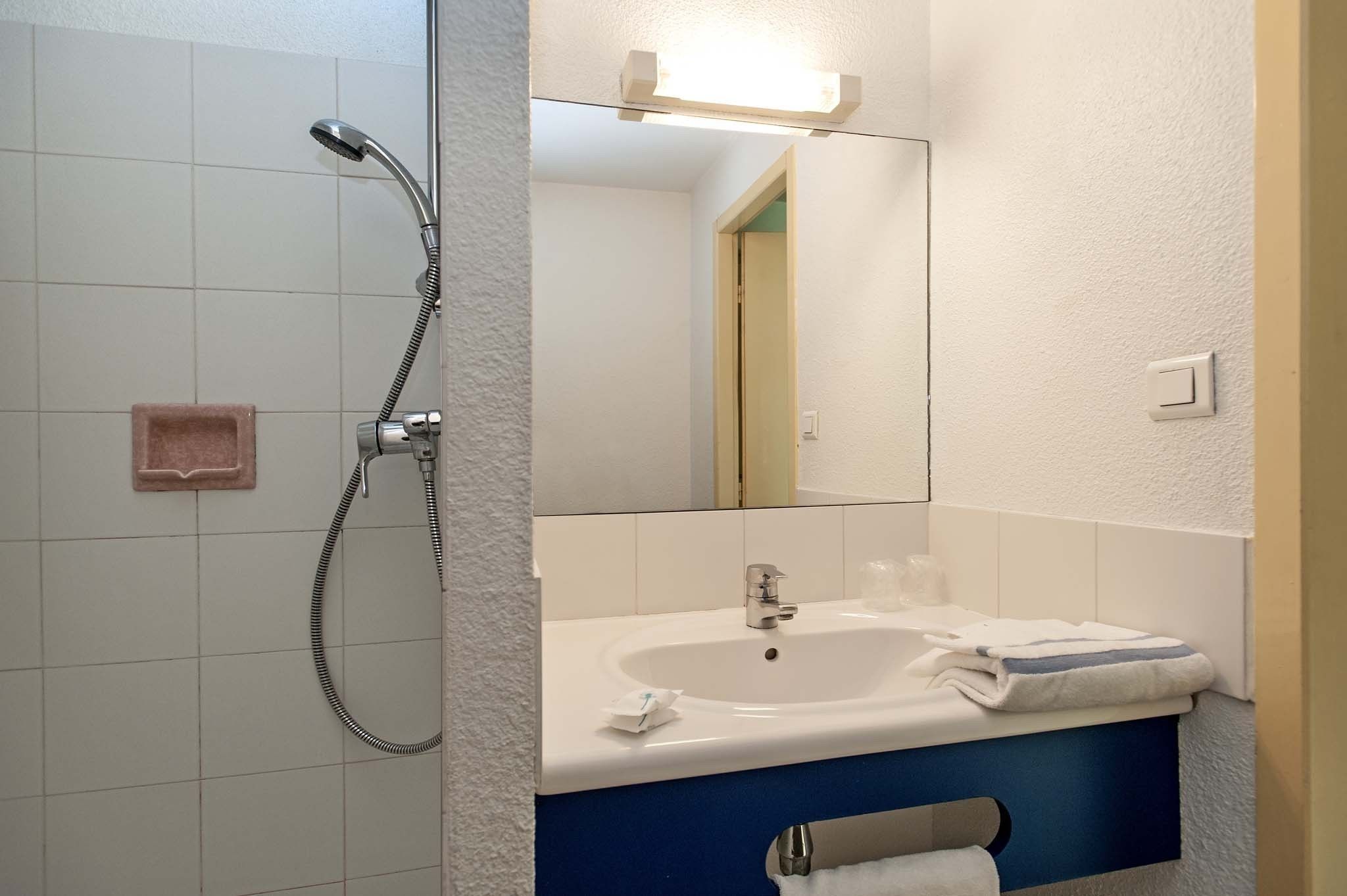 Un baño con ducha, lavamanos y espejo.