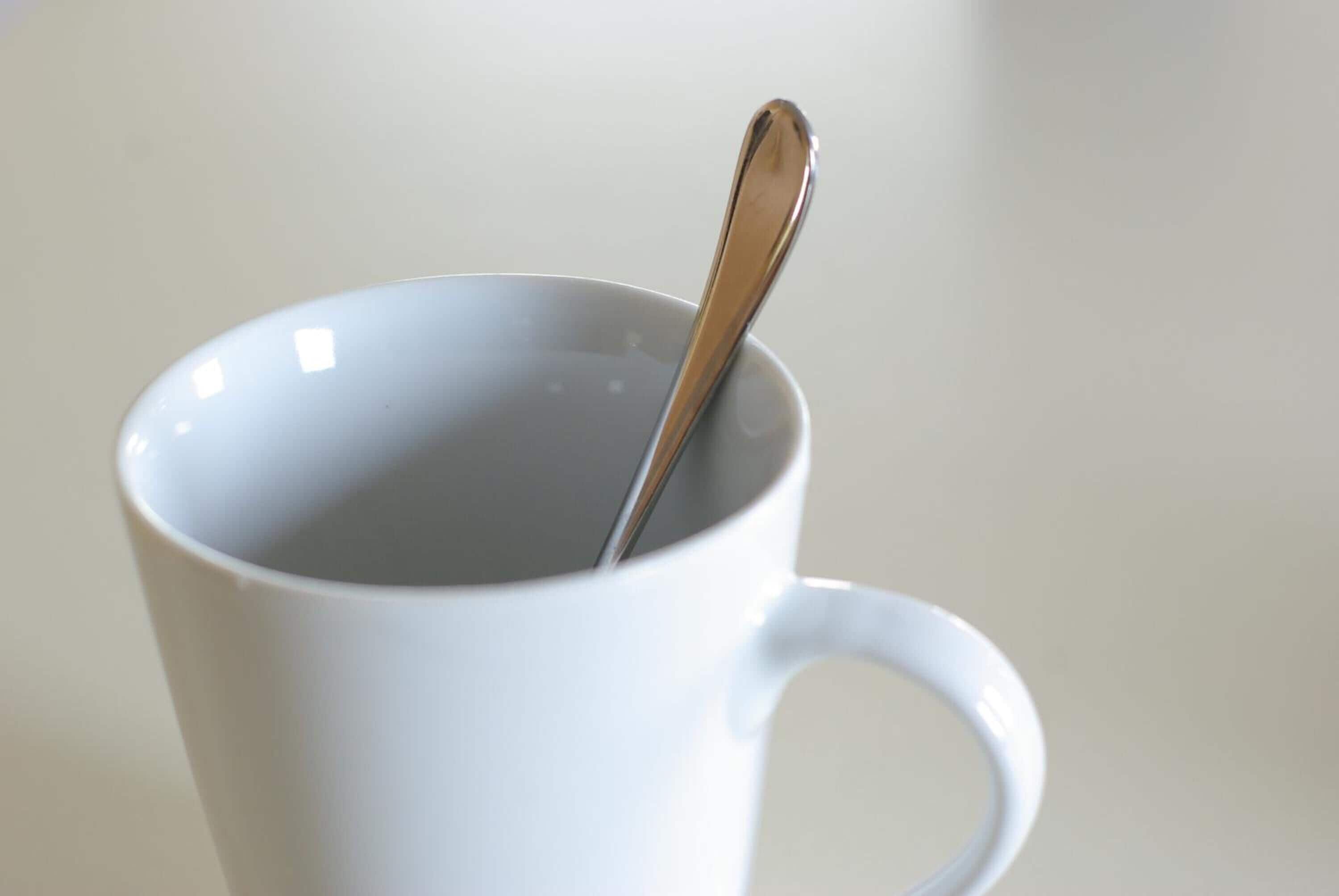 A white ceramic mug with a spoon inside.