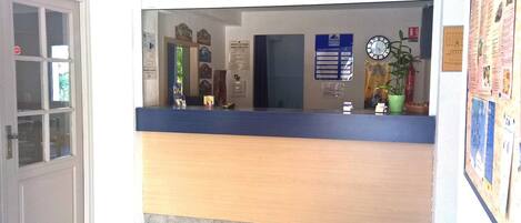 A reception desk with a blue counter, a clock, and various informational posters on the wall.