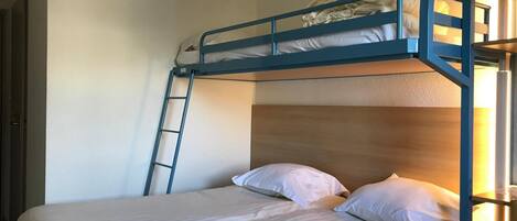 A bunk bed with a wooden headboard, a ladder, and two pillows.
