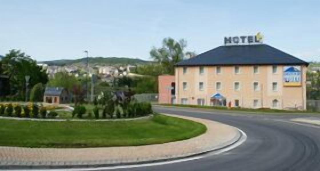 Ein Hotel mit Schild, das es als Motel kennzeichnet, umgeben von einer angelegten Grünfläche, mit einer geschwungenen Zufahrt.
