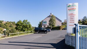 A BRIT HOTEL sign with amenities including 1-4 persons accommodation, free WiFi, Canal+ and CB 24/24. - Brit Hotel Essentiel St Flour (Saint-Flour)