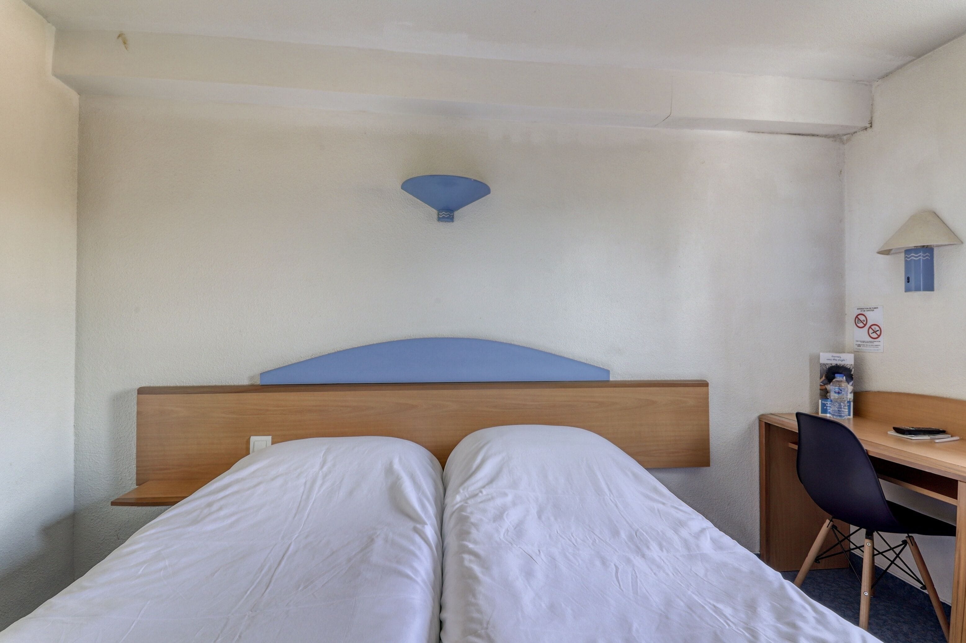 A hotel room with a bed, a desk, and a chair.