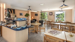 A breakfast area with a counter, seating, and a view of the outdoors. - Brit Hotel Essentiel St Flour (Saint-Flour)