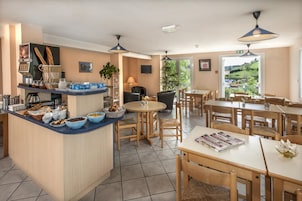 Un área de desayuno con mostrador, asientos y vista al exterior.