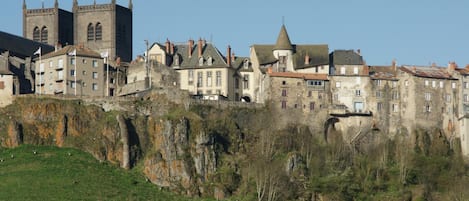 Uma cidade histórica com edifícios de pedra, uma torre de igreja imponente e um penhasco íngreme.