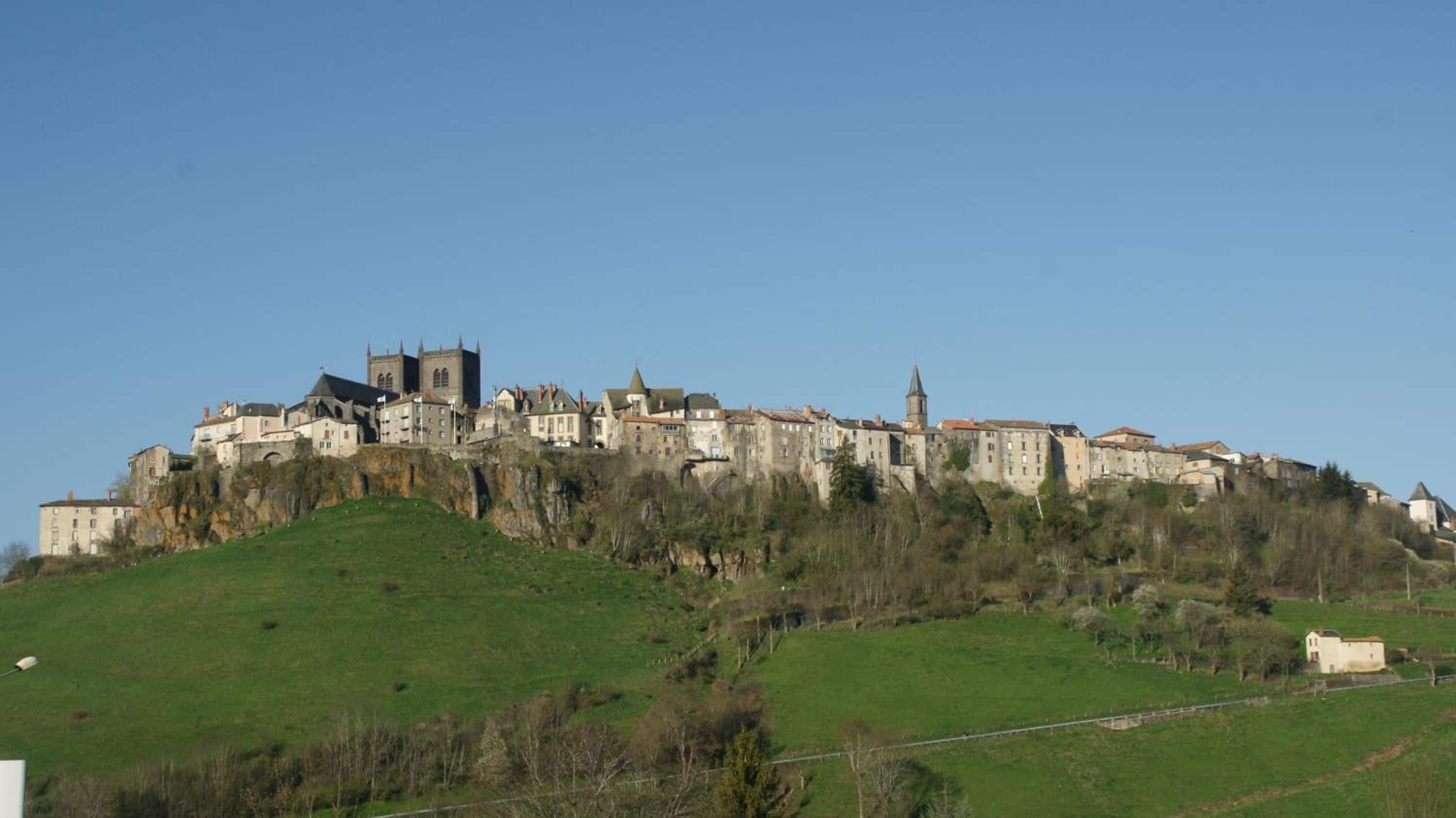 A historic castle on a hill with multiple buildings, including a prominent tower.