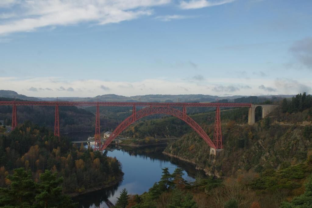 A red bridge over a river with a mountainous backdrop.
