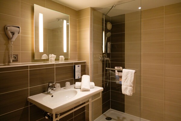 Un baño moderno con lavamanos, espejo y ducha.