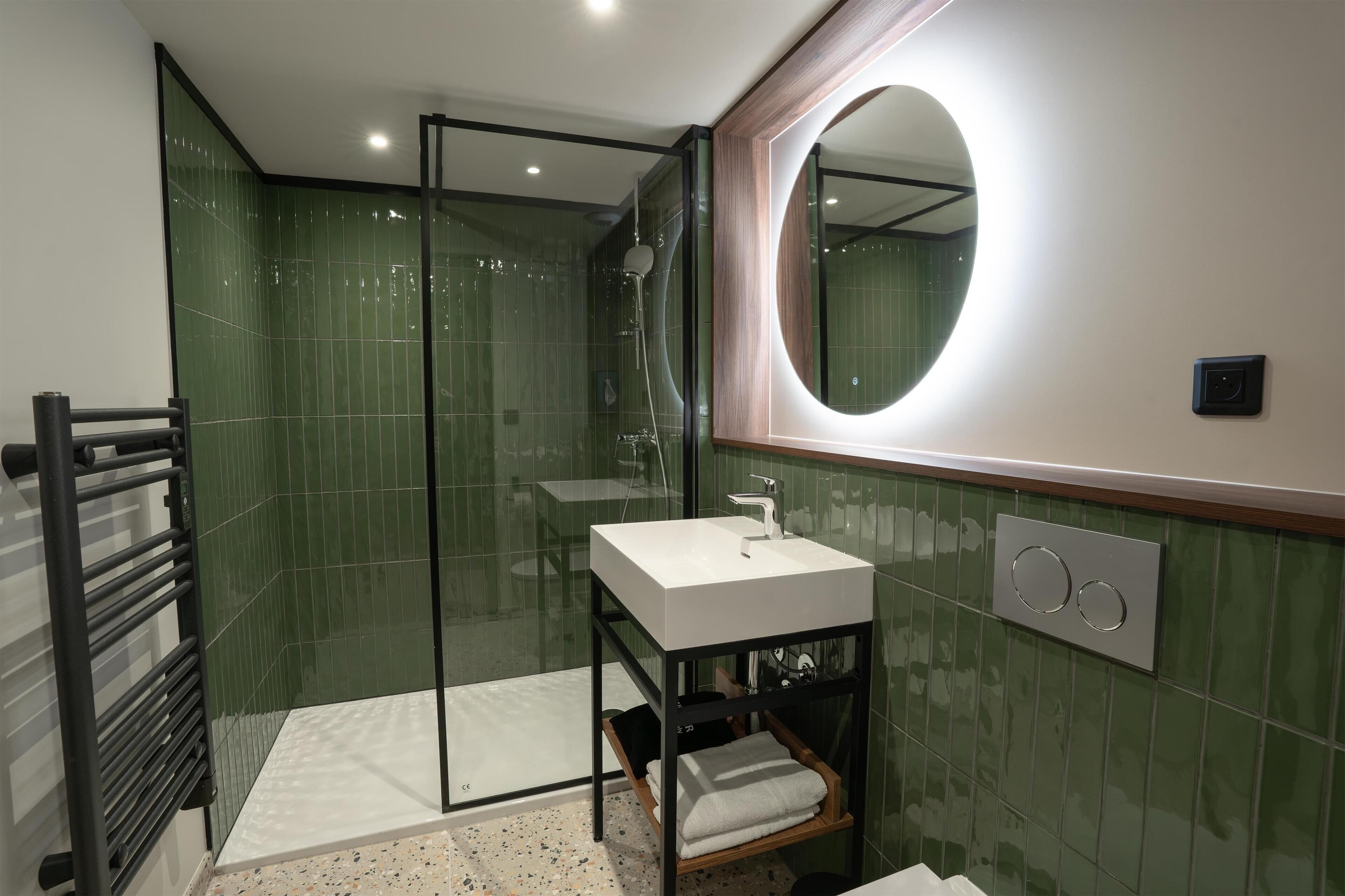 A modern bathroom with a glass shower enclosure, a white sink, and a large mirror.
