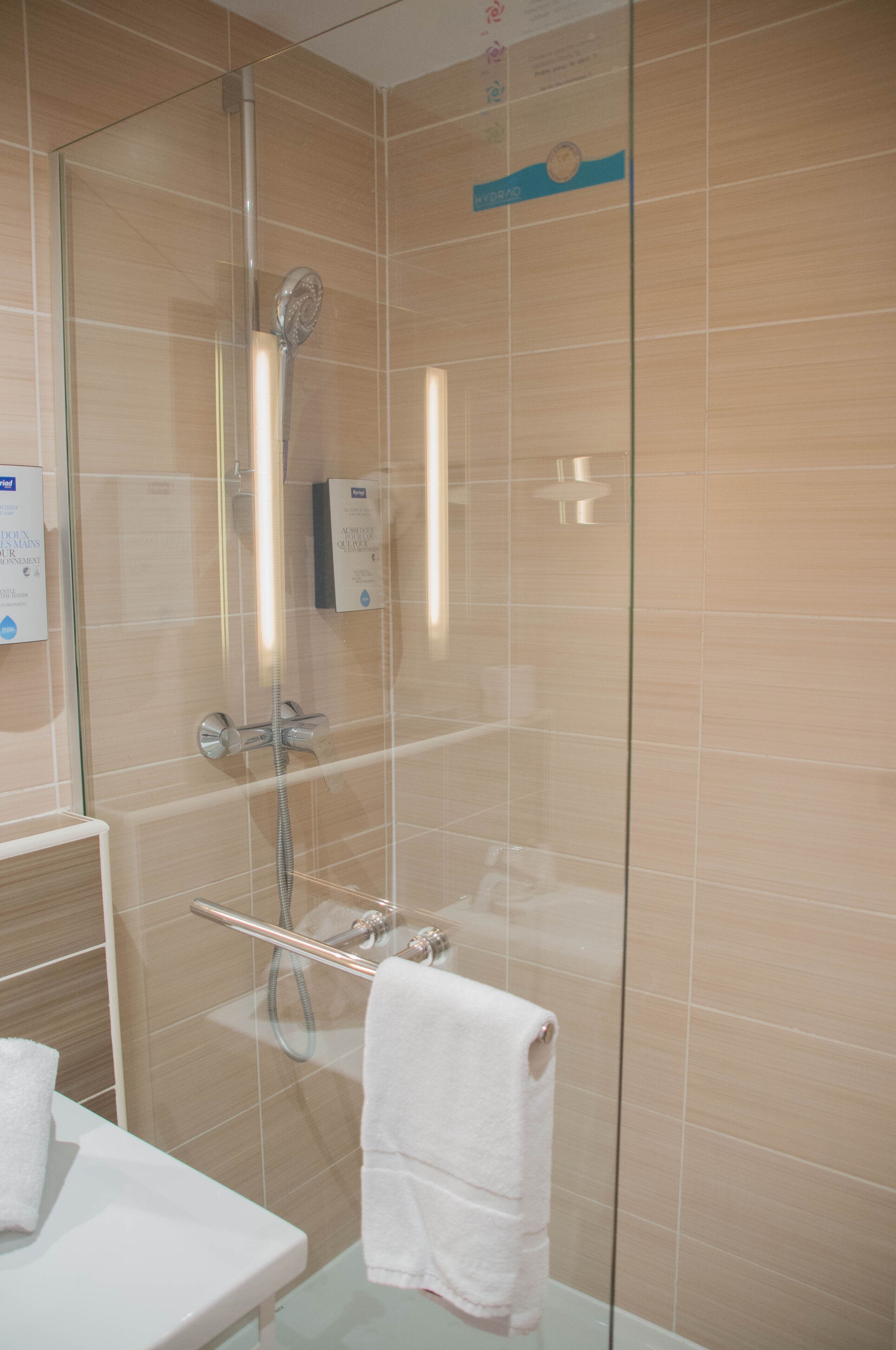 Ein modernes Badezimmer mit Duschkabine aus Glas, einem weißen Waschbecken und einem Handtuchhalter.
