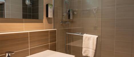 A modern bathroom with a large mirror, a sink, a shower, and a towel rack.