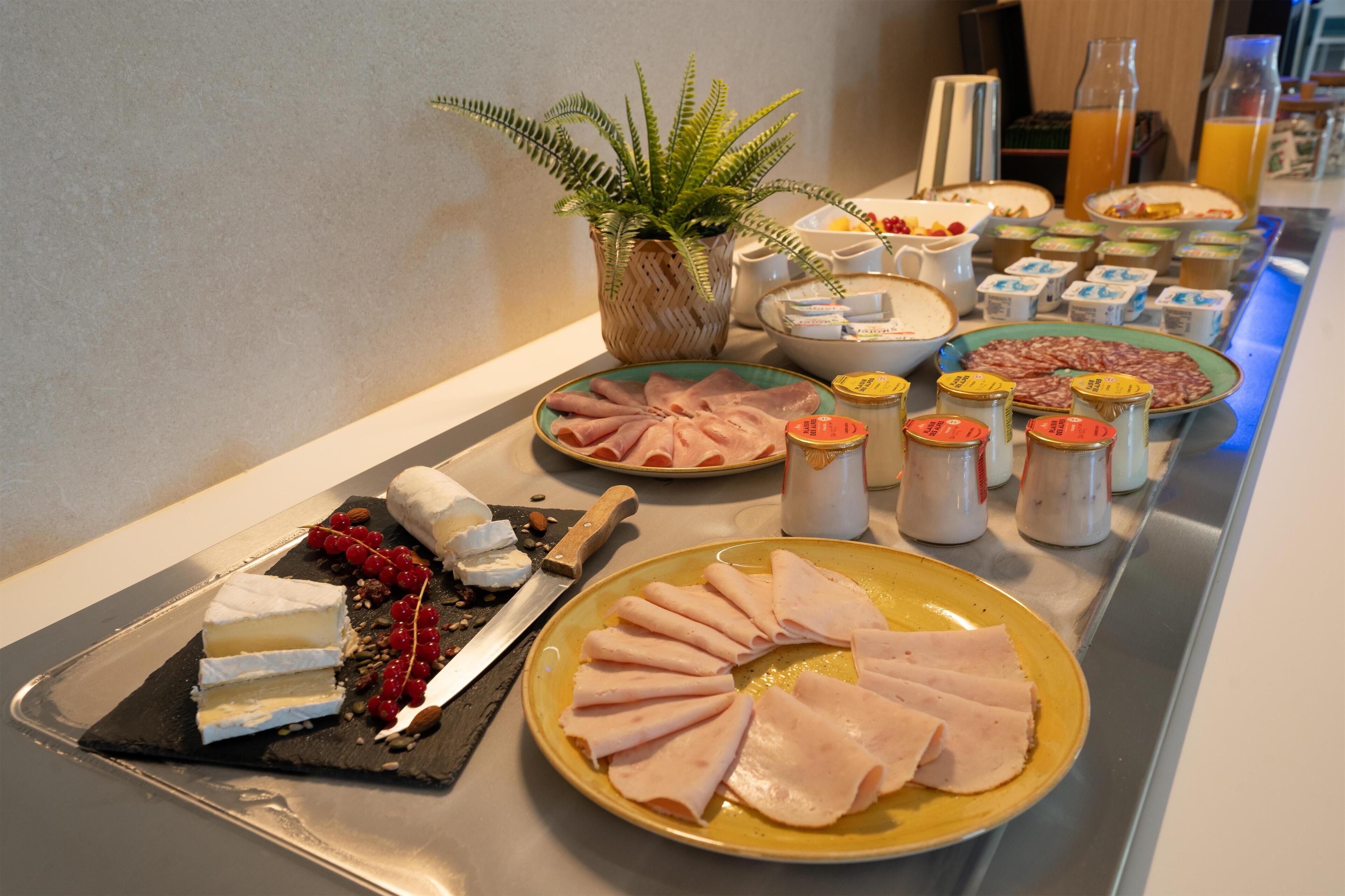 A buffet with various food items including meats, cheeses, and condiments.