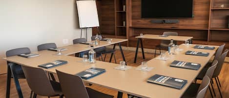 A conference room with a large screen, multiple tables, and chairs.