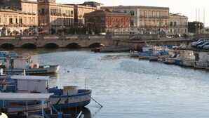 Un puerto deportivo con barcos amarrados, un puente de piedra y edificios históricos al fondo.