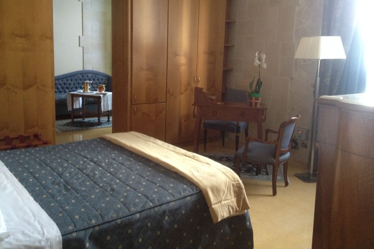 A bedroom with a bed, a desk, a chair, and a wardrobe.