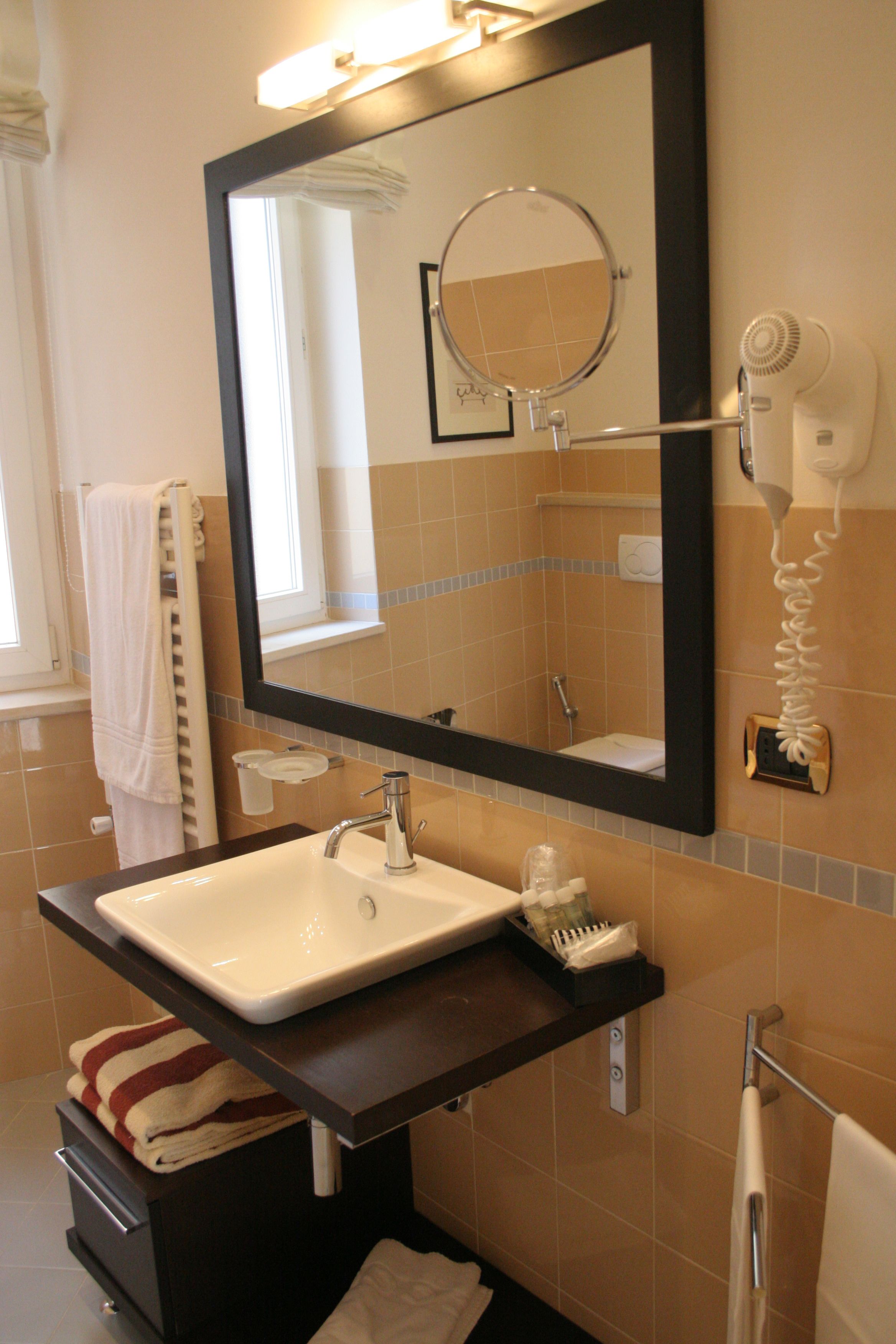 A bathroom with a large mirror, a sink, a towel rack, and a hairdryer.