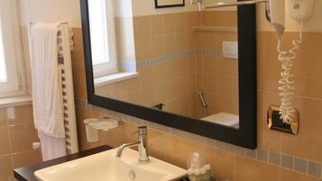 A bathroom with a large mirror, a sink, a towel rack, and a hairdryer.