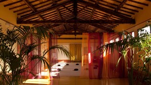 A room with a high wooden ceiling, large windows, and potted plants. - Podere Violino (Sansepolcro)