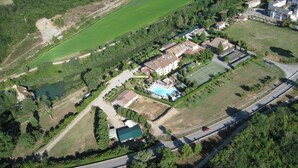 An aerial view of a residential area with a large building, a tennis court, and a swimming pool. - Podere Violino (Sansepolcro)