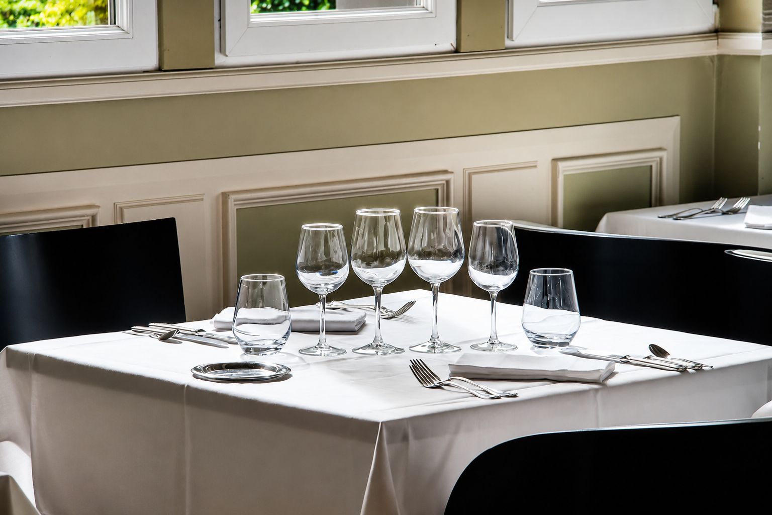 A dining table set with multiple wine glasses, plates, and cutlery, indicating a formal dining arrangement.